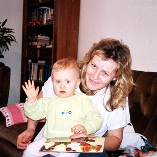 Mother and baby playing with picture book indoors.