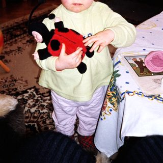 Baby holding red and black stuffed toy.