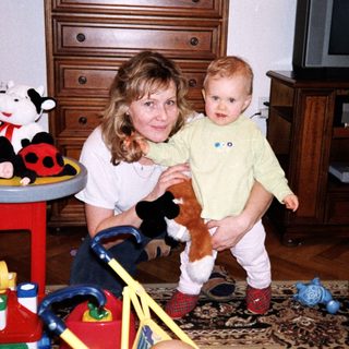 A woman holding a young child in a playful indoor setting.