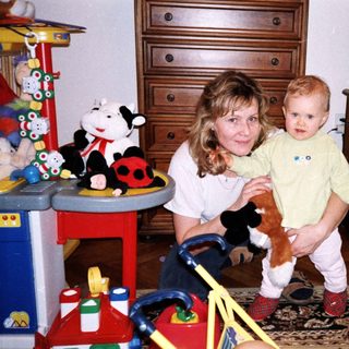 A woman holding a young child in a playful indoor setting.