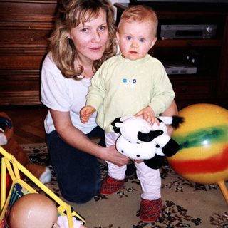 A woman holding a toddler with a cow plush toy.