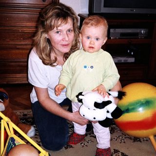 A woman holding a toddler with a cow plush toy.
