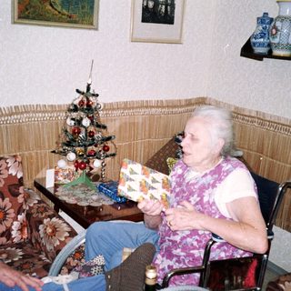 Two people in a cozy room, one holding gift-wrapped box.
