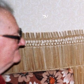 Two people in a cozy room, one holding gift-wrapped box.