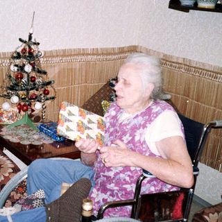 Two people in a cozy room, one holding gift-wrapped box.