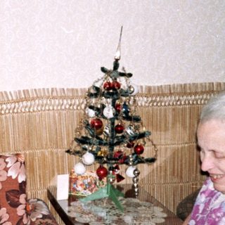 Two elderly people crafting together indoors.
