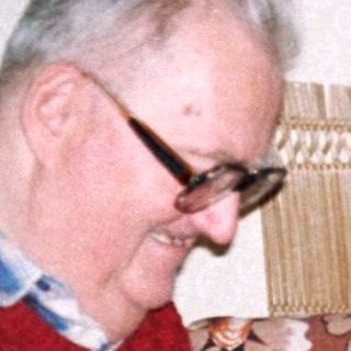 Two elderly people crafting together indoors.