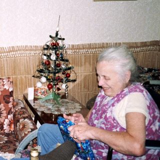 Two elderly people crafting together indoors.
