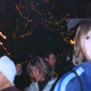 Fireworks display over illuminated Christmas tree.