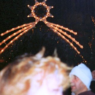 Fireworks display over illuminated Christmas tree.