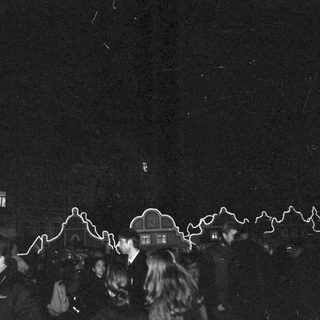 Nighttime crowd with illuminated light trails.