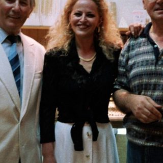 Three people posing indoors together in formal attire.
