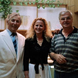 Three people posing indoors together in formal attire.