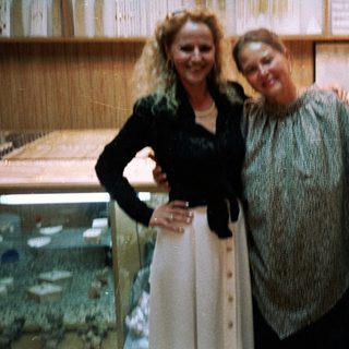Three people posing indoors near aquarium tanks.