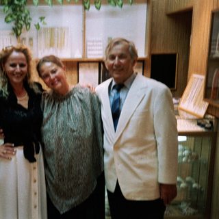 Three people posing indoors near aquarium tanks.