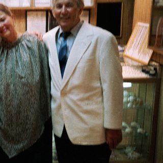 Three people posing indoors near aquarium tanks.