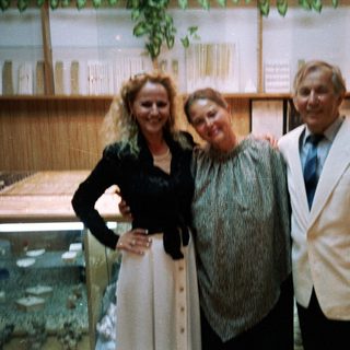 Three people posing indoors near aquarium tanks.