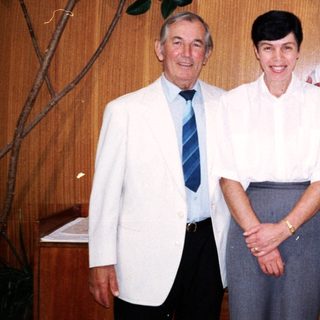 Three adults posing together indoors in formal attire.