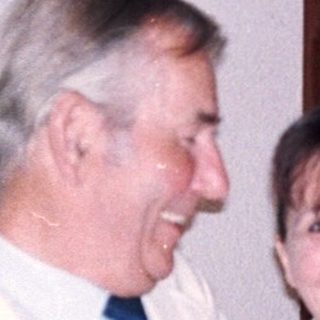 Two people smiling indoors near a door.