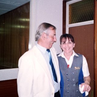 Two people smiling indoors near a door.