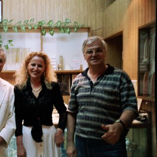 Three people posing indoors together in casual business attire.