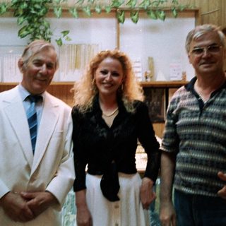 Three people posing indoors together in casual business attire.