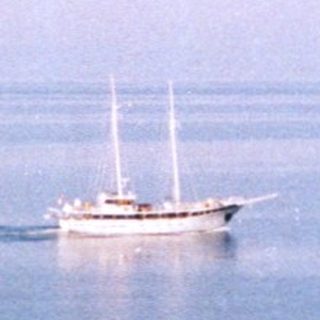 Scenic coastal view with sailboat on calm sea.