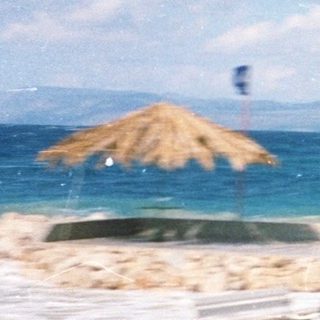 Person walking near seaside with beach umbrellas.