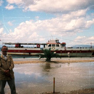 Man standing by waterfront near decorated ferry boat.