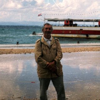 Man standing by waterfront near decorated ferry boat.
