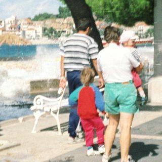 Family walking near coastal promenade with ocean waves.