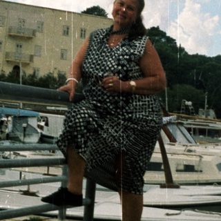 Woman sitting by marina on cloudy day.