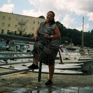 Woman sitting by marina on cloudy day.