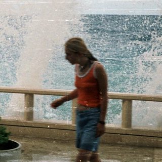 Two women enjoying ocean water fountain by seaside.