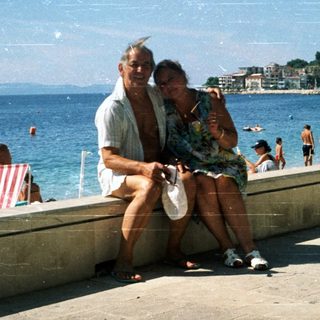 Happy couple posing by seaside promenade.