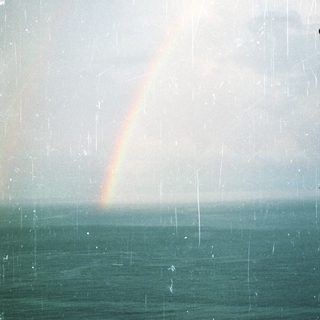 Rainbow over ocean during heavy rain.
