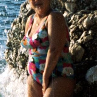 Woman stepping into clear coastal waters.