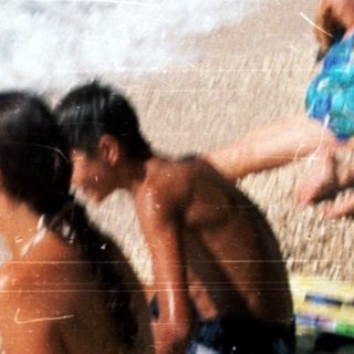 Beach scene with people relaxing near waves.