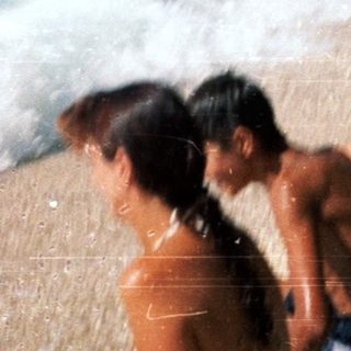 Beach scene with people relaxing near waves.
