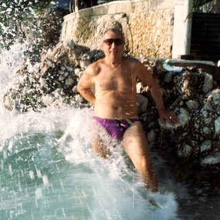 Shirtless person jumping into a waterfall.
