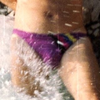 Shirtless person jumping into a waterfall.