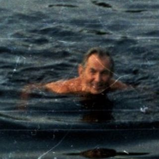 Person swimming in calm, reflective water.