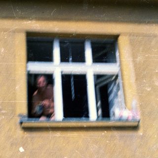 Person peering out from a barred window.