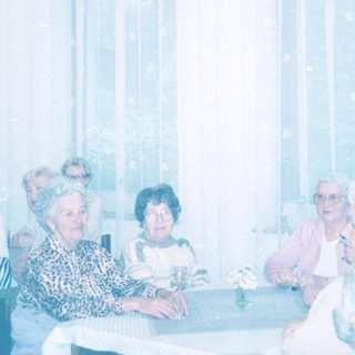 Group of elderly people gathered indoors in a communal setting.