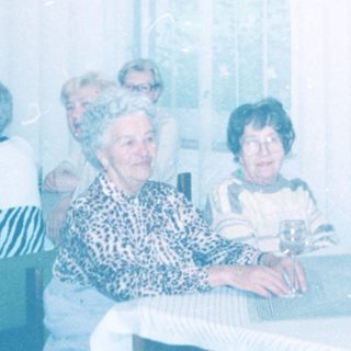 Group of elderly people gathered indoors in a communal setting.