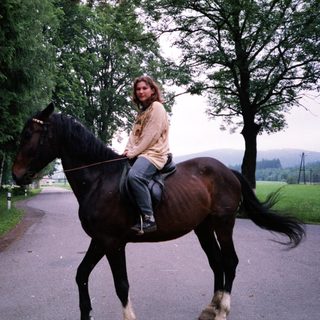 Woman riding horse on country road.