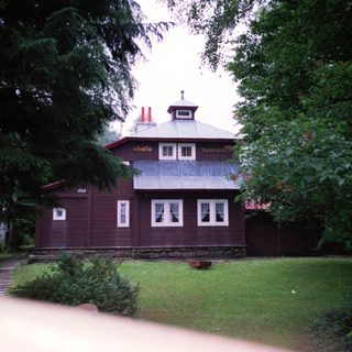 Chalet-style wooden house in forested area.