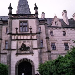 Gothic-style castle entrance with coat of arms.