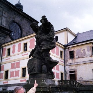 Man pointing at historic statue of knight on horse.