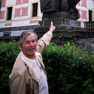 Man pointing at historic statue of knight on horse.